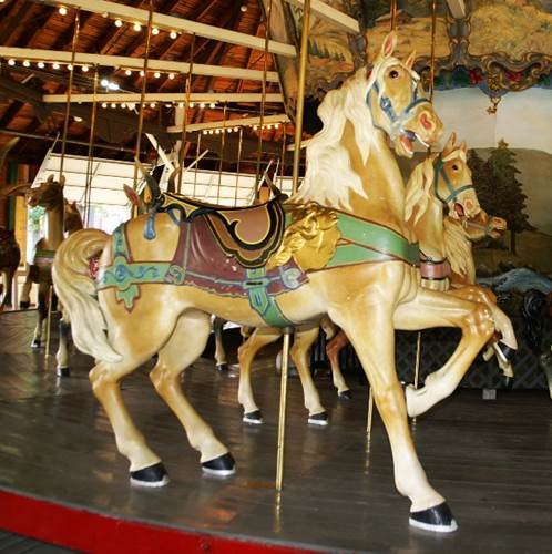 A carousel with horses on a wooden floor

Description automatically generated