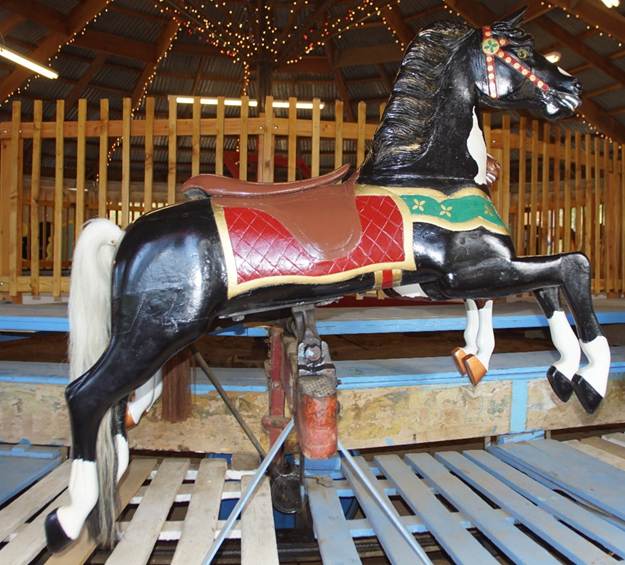 A horse statue in front of a wooden chair
Description automatically generated