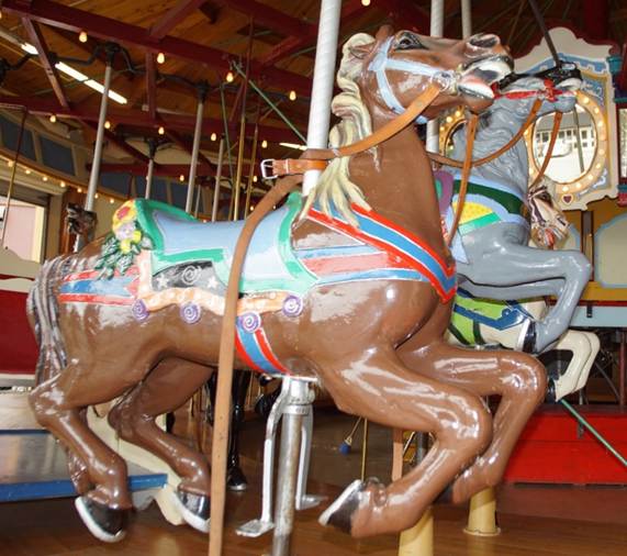 A horse statue in front of a carousel

Description automatically generated