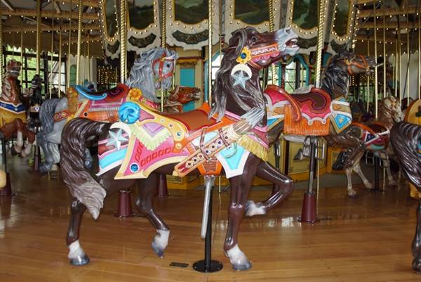 A group of people standing in front of a carousel

Description automatically generated